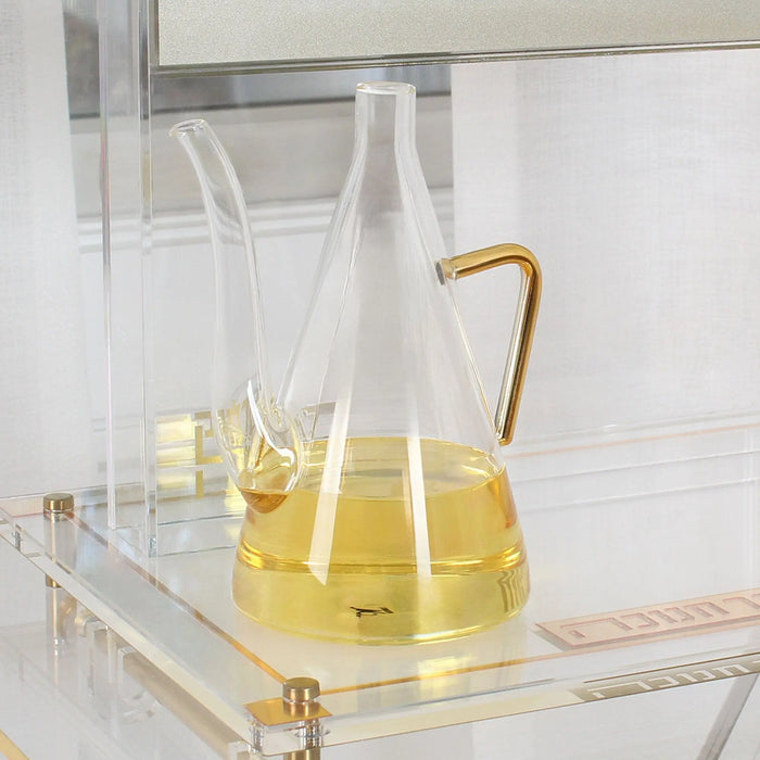 Glass oil jug filled with olive oil, its long spout ready to fill menorah cups for Chanukah