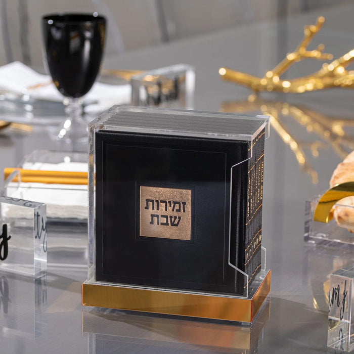 Black and gold hardcover leather bencher set with lucite accents displayed on white surface with holiday decorations nearby.