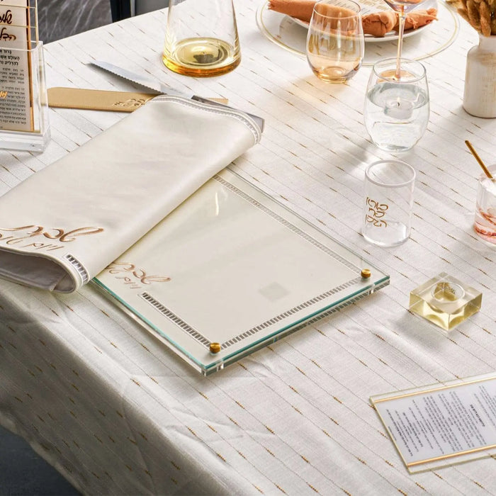 Hemstitch Challah Board in cream with delicate embroidered border detail, styled on white table with place settings and wine glasses for Shabbat dinner.