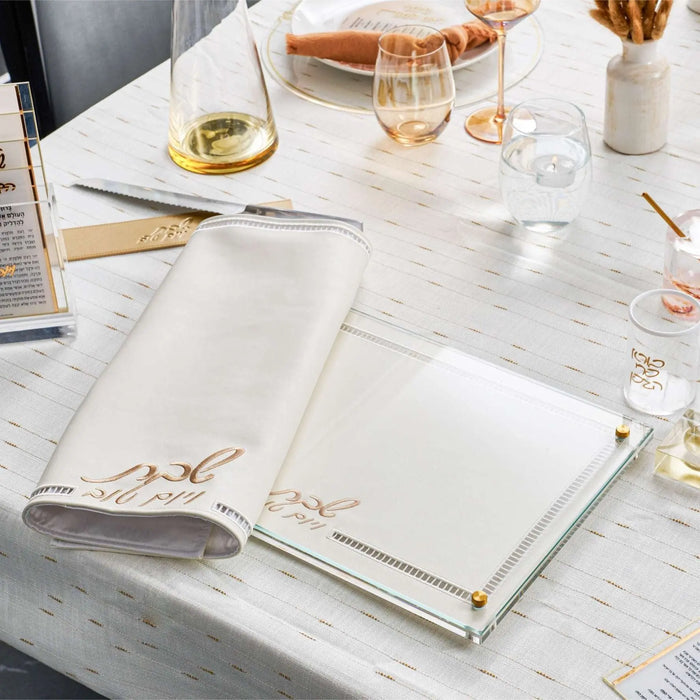 Waterdale Collection hemstitch challah board displayed on marble surface with wine glasses and place settings for Shabbat dining.