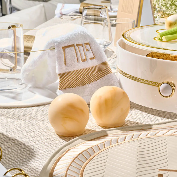 Beige herringbone hand towel displayed with gold table settings and decorative items on a neutral surface, styled for Pesach entertaining.