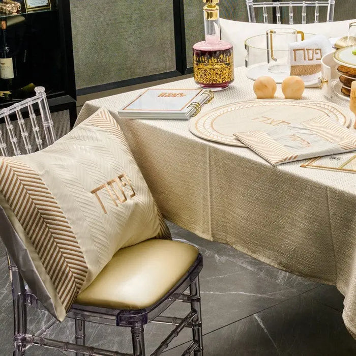 Herringbone Pesach set in gold and white leather displayed on table with matching pillows and place settings for holiday dining.