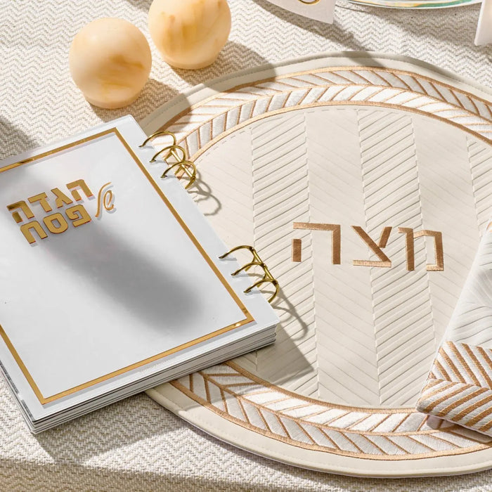 Herringbone Matzah cover in cream leather with geometric woven pattern, displayed on table setting with matzah and Passover tableware.