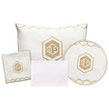 Hexagon Pesach set featuring white pillows and round plate with gold hexagon emblem, elegant leather tabletop collection