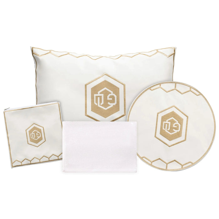 Hexagon Pesach set featuring white pillows and round plate with gold hexagon emblem, elegant leather tabletop collection