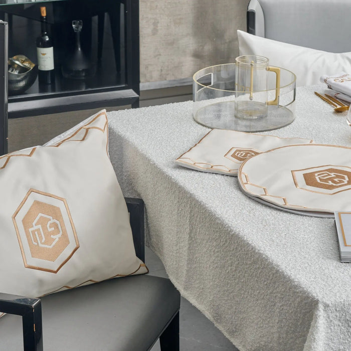 Hexagon Pesach set with white linen tablecloth, matching pillow, and gold geometric tableware arranged on table with leather accents