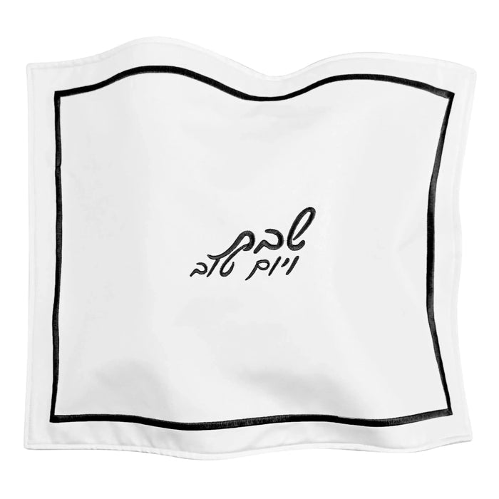 White leather challah cover with black wavy border and Hebrew text, elegant hotel style design for Shabbat table.