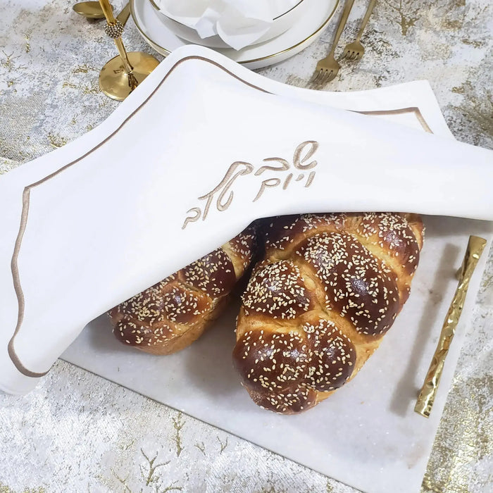 Hotel Style Challah Cover in gold and black leather with bread and knife on white surface, Shabbat tabletop