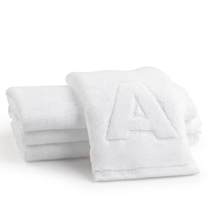 White embossed finger towels with monogram initial design, folded stack on white background, soft cotton blend material for vanity or guest use.