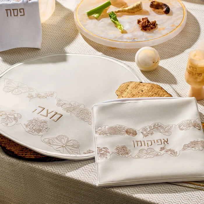 Inlay Floral Pesach Set by Waterdale Collection featuring white leather plates with gold and silver inlay details arranged on a table with matzah and Passover items.
