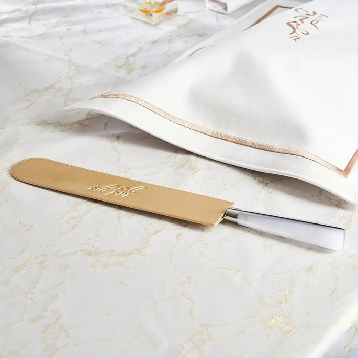 Waterdale Collection leather knife blade cover in tan with metal ferrule, displayed on marble surface next to wooden challah board knife.