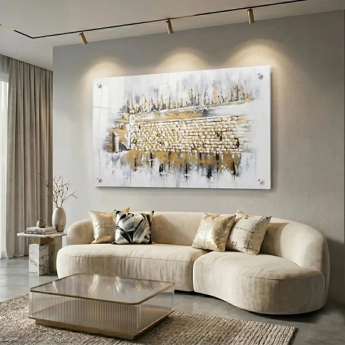 Kosel at Winter Painting displayed above a curved cream sofa in a modern living room, featuring a watercolor Jerusalem artwork in gold and blue tones.