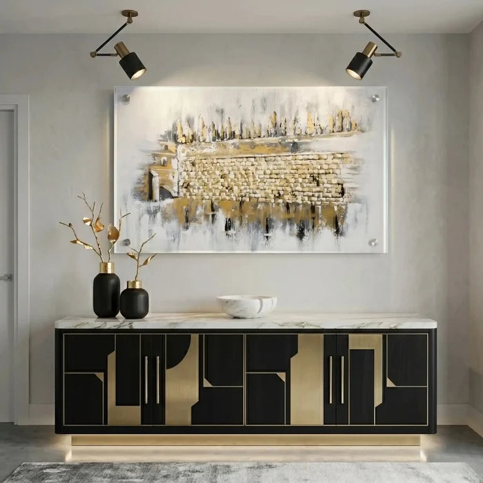 Kosel at Winter painting displayed above a black sideboard with gold accents in a modern home setting with track lighting.