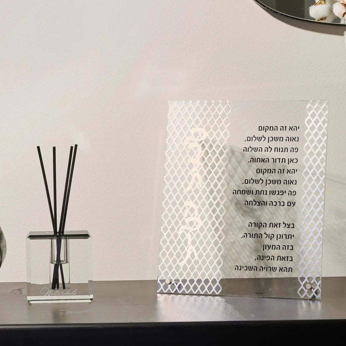 White laser cut tabletop Birchas Habayis plaque displayed next to a reed diffuser on a dark shelf