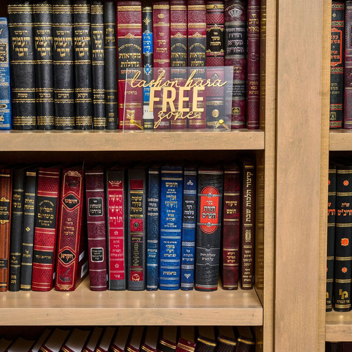 Lashon Harah Free wooden tabletop plaque displayed on a bookshelf among leather-bound books, featuring engraved text in a natural wood finish.