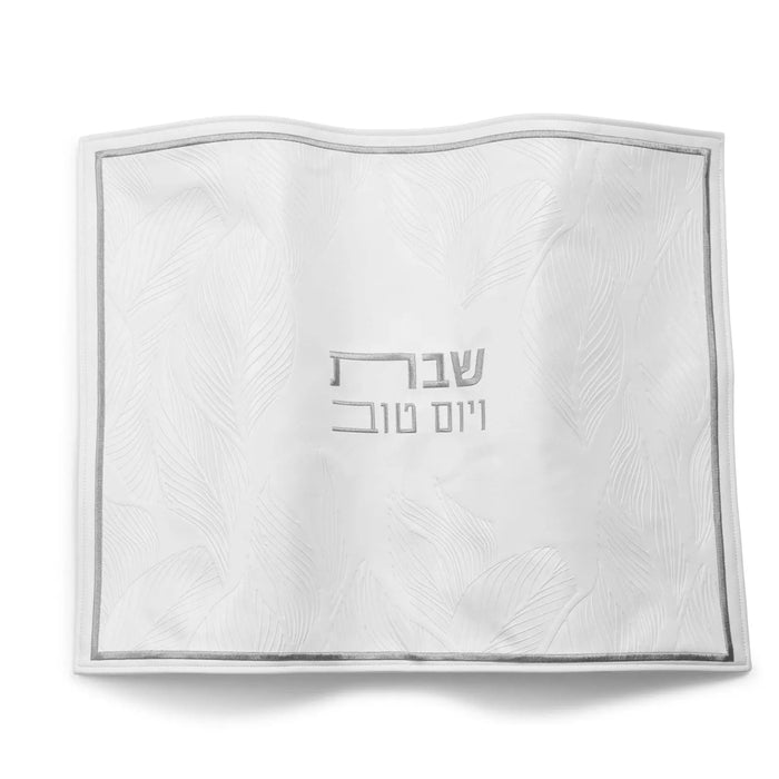 White leather challah cover with silver border and Hebrew text, classic design for Shabbat table.