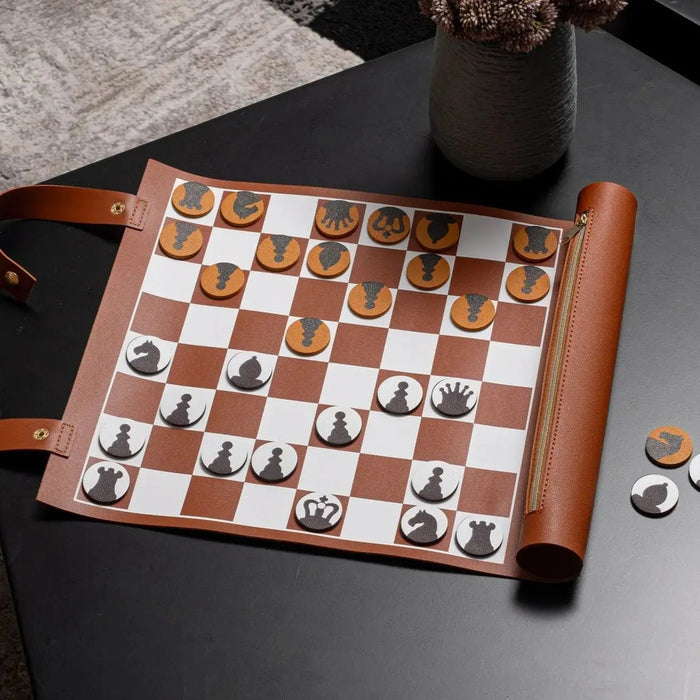 Leather chess and checkers set with brown and white board, wooden pieces, and leather trim displayed on dark surface.