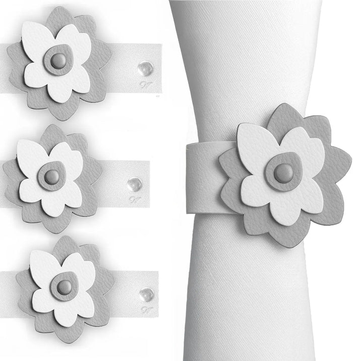 Set of four gray leatherette flower napkin wraps with pearl centers, displayed on folded white napkins for table setting.
