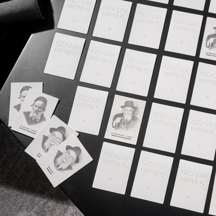 Black leather Gedolim matching game with portrait cards displayed on grid board, perfect for family game nights and Jewish educational play.