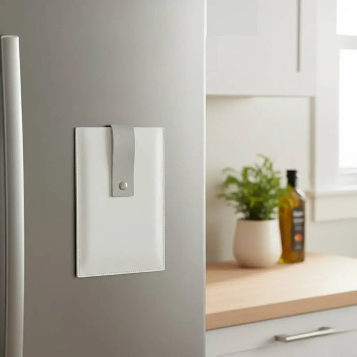White leather kitchen card magnet set displayed on refrigerator door next to wooden countertop and potted plant.