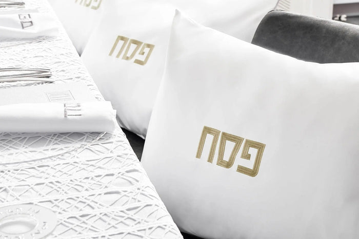 White leather pillow case with gold embroidered Waterdale Collection logo, displayed with architectural blueprints