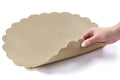 Tan leather scalloped charger plate with decorative wavy edges, displayed at an angle against a white background.