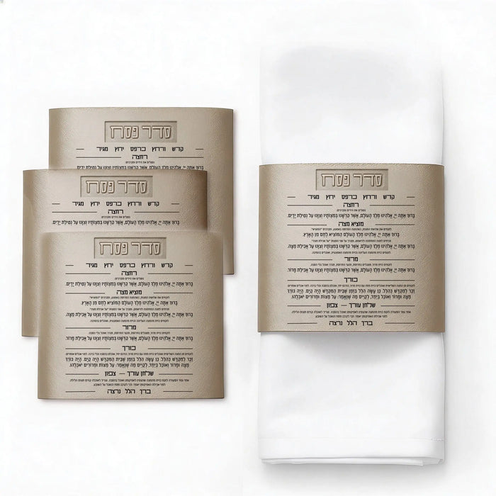 Leather Seder card napkin wraps in gold and silver displayed on white napkins, showing printed Haggadah text on tan leatherette material for Pesach table setting.