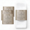 Leather Seder card napkin wraps in gold and silver displayed on white napkins, showing printed Haggadah text on tan leatherette material for Pesach table setting.