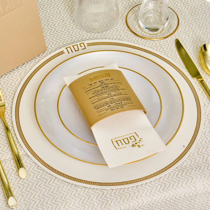 Gold leather Seder card napkin wrap placed on a formal place setting with gold-rimmed plates and matching napkin ring holder for Pesach.