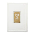 White leather Tehillim book with gold decorative lucite plate featuring Hebrew text and ornamental corner details.