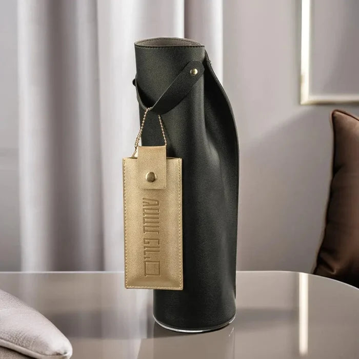 Black leather wine bag with tan accent tag by Waterdale Collection, displayed on white surface with lifestyle styling.