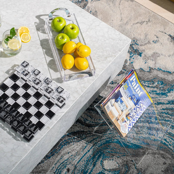 Luxe bread tray in polished metal with gold and green serving pieces displayed on marble surface, styled with chess set and decorative items.