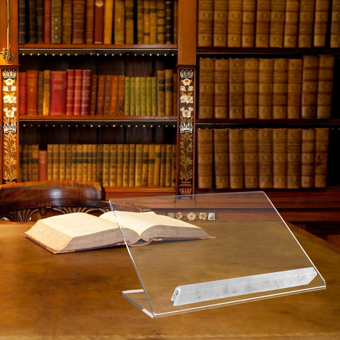 Clear acrylic Luxe Tabletop Shtender displayed on wooden desk with open book, library shelves in background.