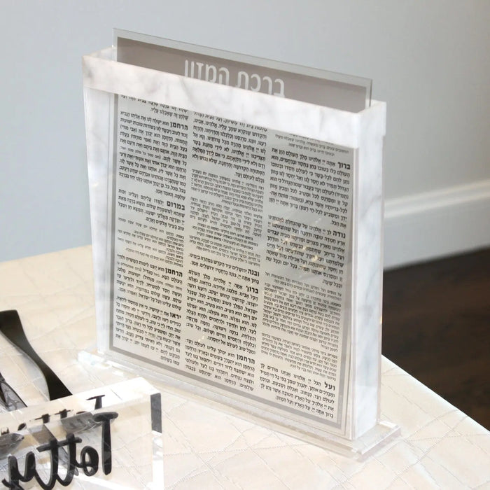 Marble & Clear Bencher Set displayed on tabletop with white marble base and acrylic holder showing Hebrew text pages for Shabbat use.