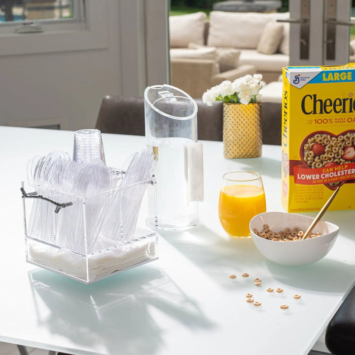 Clear acrylic MetaLucite Twig Swivel Silverware Caddy holding utensils on white countertop with juice and cereal box.