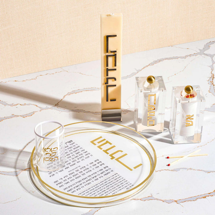 Minimalist Havdalah candle set with gold accents, including tall braided candle, matches, and circular holder on white surface