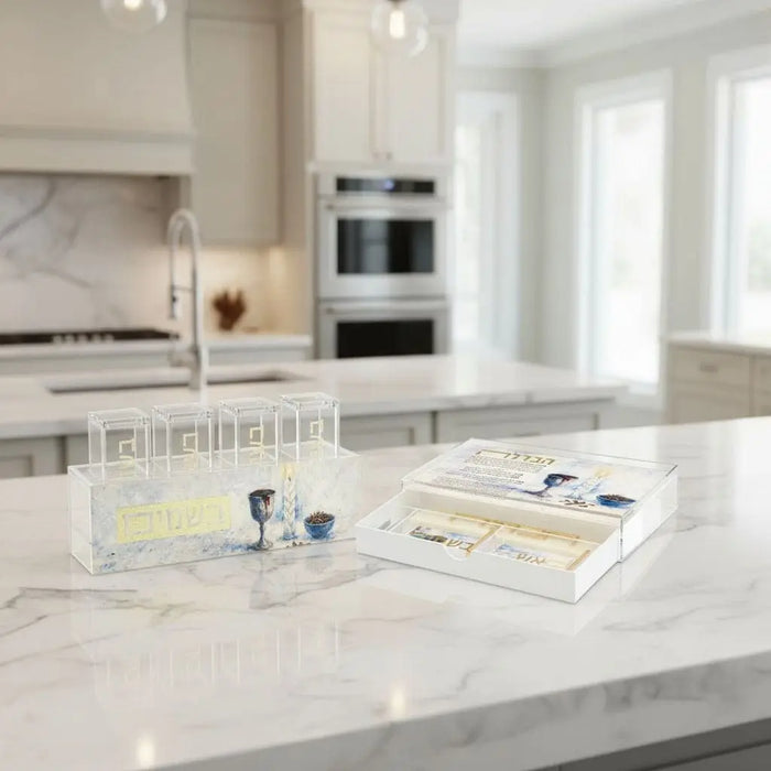 Painted besamim jars from Waterdale Collection displayed on a white marble kitchen counter, featuring decorative match holders in classic style for Shabbat and entertaining.