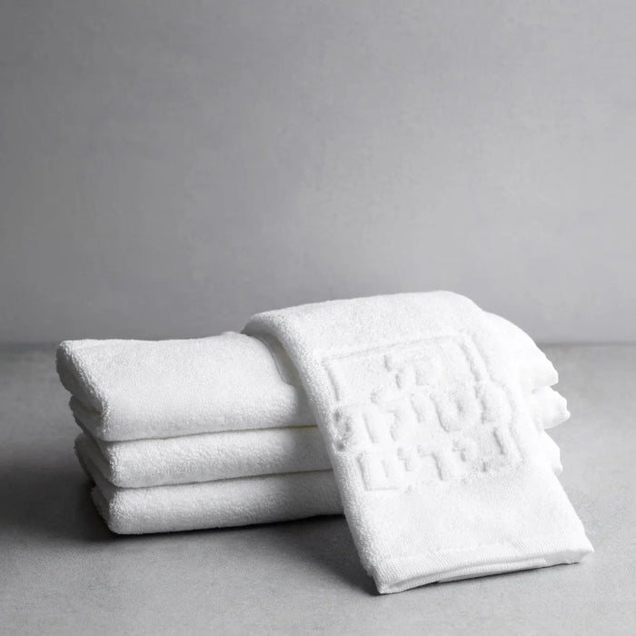 Waterdale Collection Netilas Yadayim embossed white finger towels stacked, showing soft cotton material and decorative texture detail for guest bathroom use.
