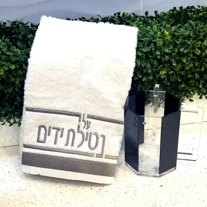 Waterdale Collection Netilas Yadayim hand towel in cream with black and silver Hebrew text stripe, displayed with matching black towel.