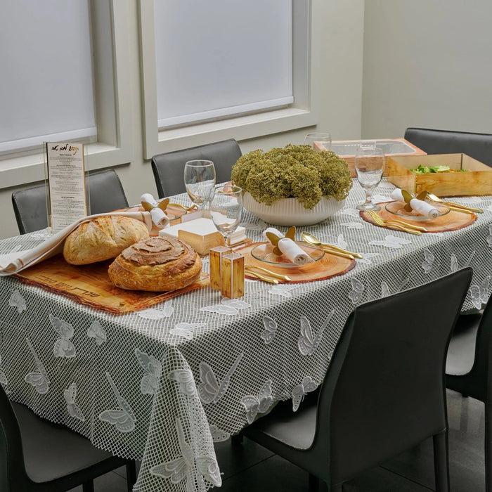 Onyx Butterfly Tablecloth with gray and white pattern displayed on table set with bread, salads, and dishes for Shabbat dinner.