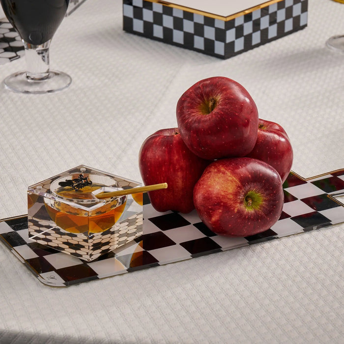Onyx Charcuterie Board with black and white checkered pattern, styled with red apples and amber drink on white surface.