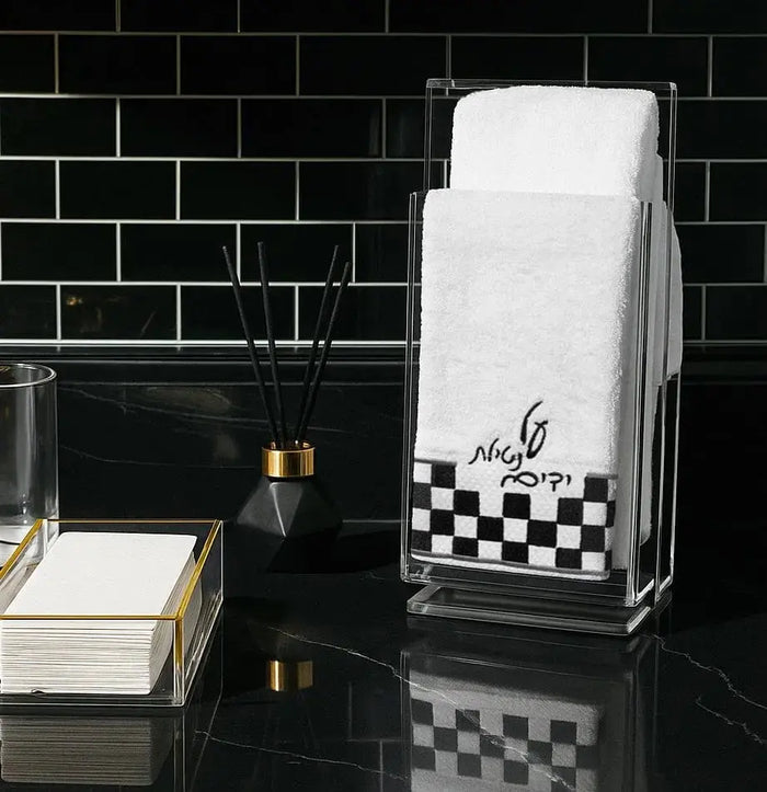 Onyx hand towel with black and white checkered pattern displayed in bathroom vanity setting with gold accents