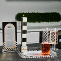 Onyx Havdalah set with black and white striped candle holder, spice container, and kiddush cup arranged on a decorative tray with greenery backdrop.
