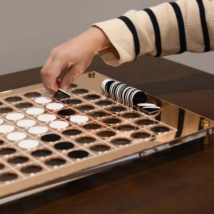 Hand placing white disc on wooden Othello game board with black and white pieces and storage tower.