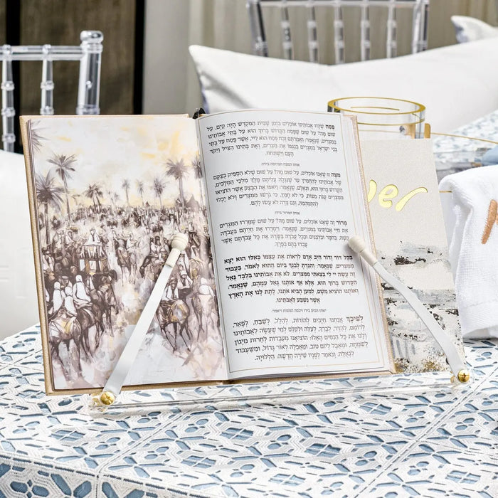 Painted Bais Hamikdash Haggadah stand holding open book on patterned tablecloth with glass of wine nearby