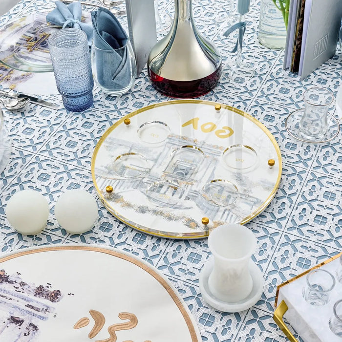 Painted Bais Hamikdash Seder Plate with gold trim displayed on patterned tablecloth, showing detailed ceramic design for Pesach holiday meals.