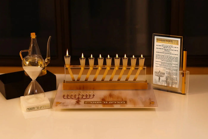 The Painted by Batya 2.0 Menorah Tray set out with a brachos card for Hanukkah lighting, its painted design under the mirrored border