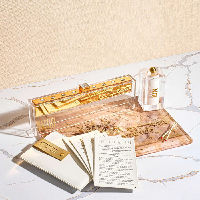 Painted by Batya Menorah Tray in gold tones styled with Chanukah candles and a brachos card on a white surface