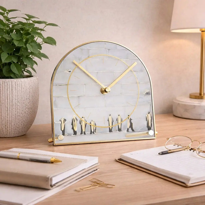 Painted by Judy Kosel Basic Desk Clock with arched top, metal frame, and gold accents displayed on wooden desk next to notebooks and plant.