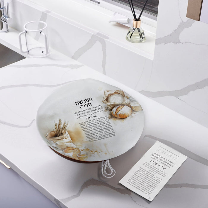 Painted Hafrashas Challah Cover in gold leather by Waterdale Collection, displayed on a white Shabbat table setting with challah and ceremonial items.